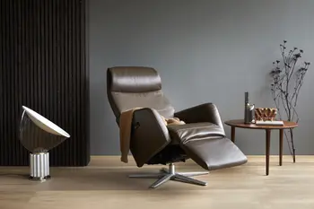 Stressless Scott Relaxsessel in der Farbe Paloma Chestnut mit Aluminium-Untergestell, ausgestattet mit Relaxfunktion. Der Sessel steht in einem stilvollen Raum mit einem runden Holztisch, dekorativen Elementen und einer modernen Lampe.